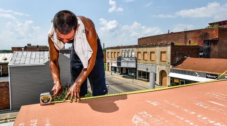 Leo Felix, with C&J Roofing, cuts underlayment while he and the crew try to stay cool as they replace rubber roofing on a building on Central Avenue Tuesday, July 18, in Middletown. NICK GRAHAM/STAFF