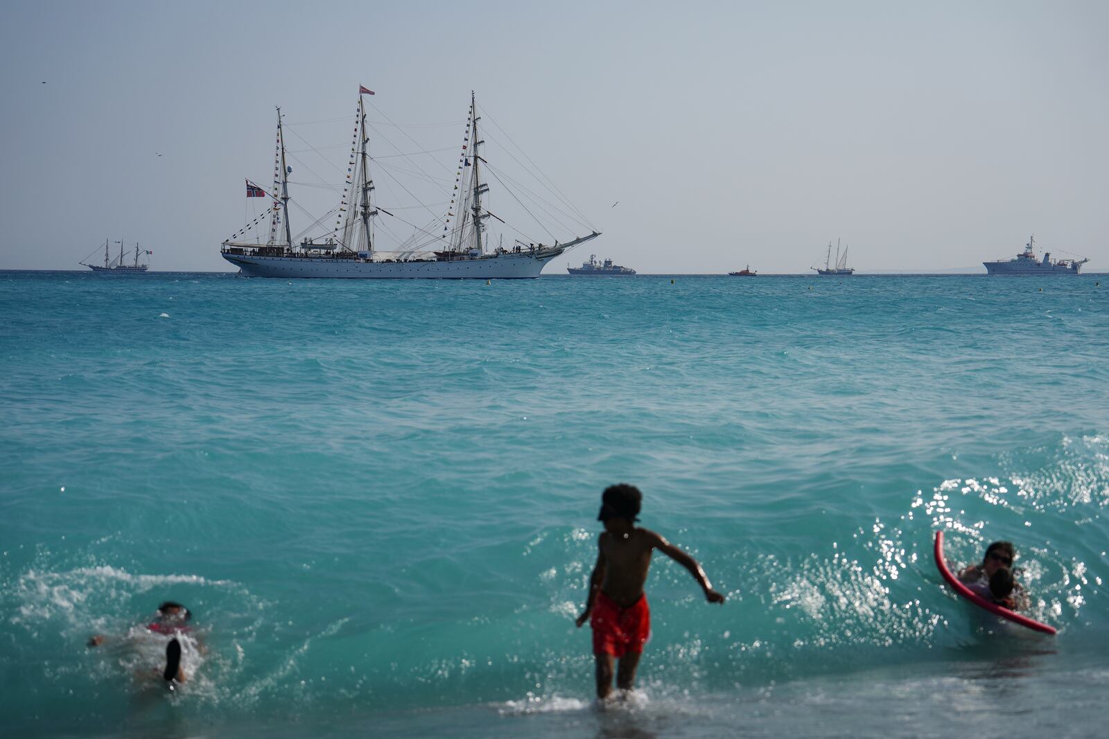 People swim as vessels sail during the "Ocean Wonders" event in honor of World Oceans Day ahead of the U.N. Ocean Conference on Sunday, June 8, 2025, in Nice, France. (AP Photo/Annika Hammerschlag)