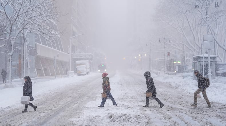 Pedestrians cross 42nd Street near Bryant Park during a snow storm, Monday, Feb. 23, 2026, in New York. (AP Photo/Seth Wenig)