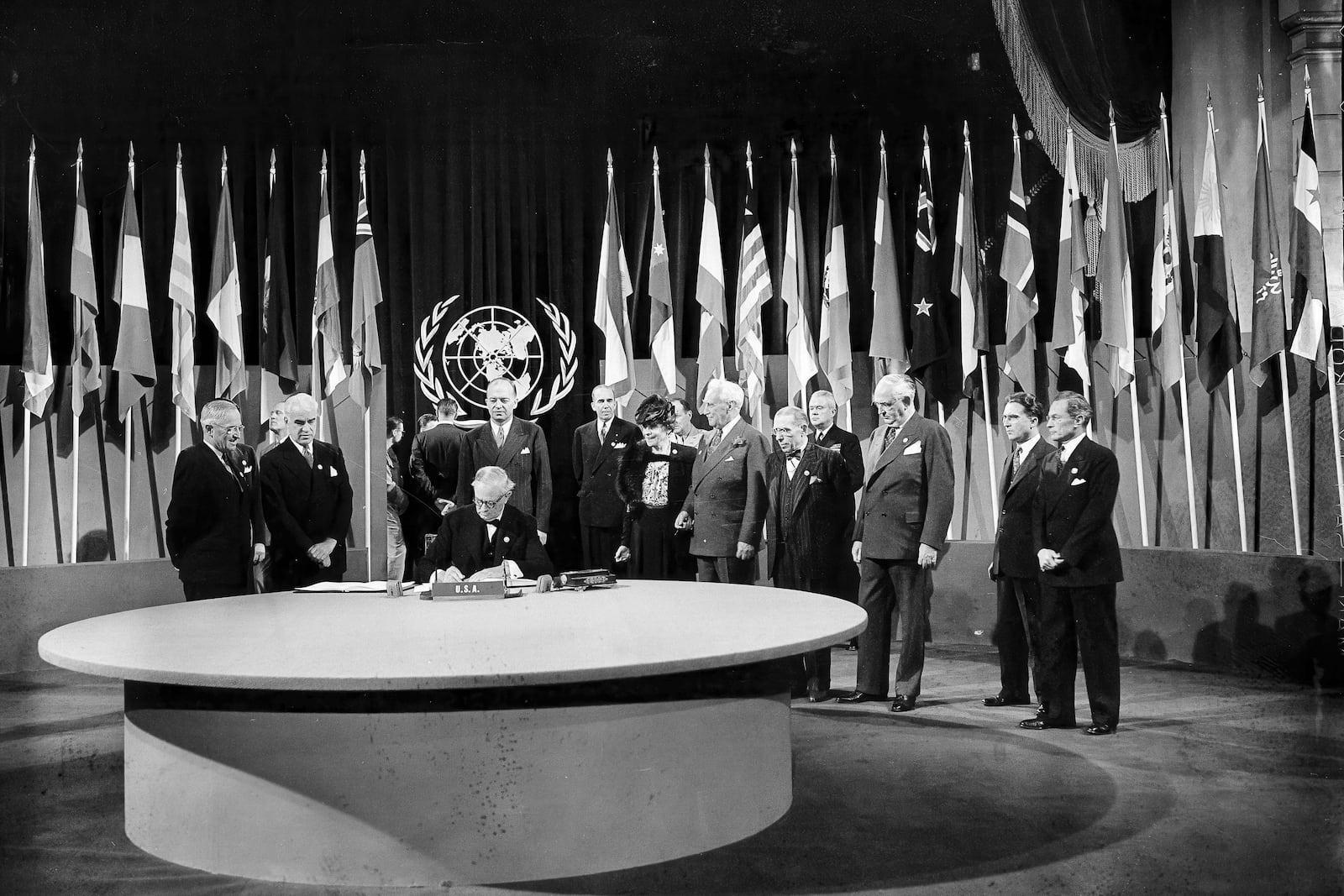 FILE - President Harry S. Truman and the entire American delegation watch as Sen. Tom Connally signs the United Nations Charter in San Francisco, June 26, 1945. Standing, from left: Truman; Secretary of State Edward Stettinius Jr.; Harold Edward Stassen; unidentified; Dean Virginia Gildersleeve; Rep. Charles A. Eaton; Rep. Sol Bloom, and Sen. Arthur Vandenberg. (AP Photo, File)