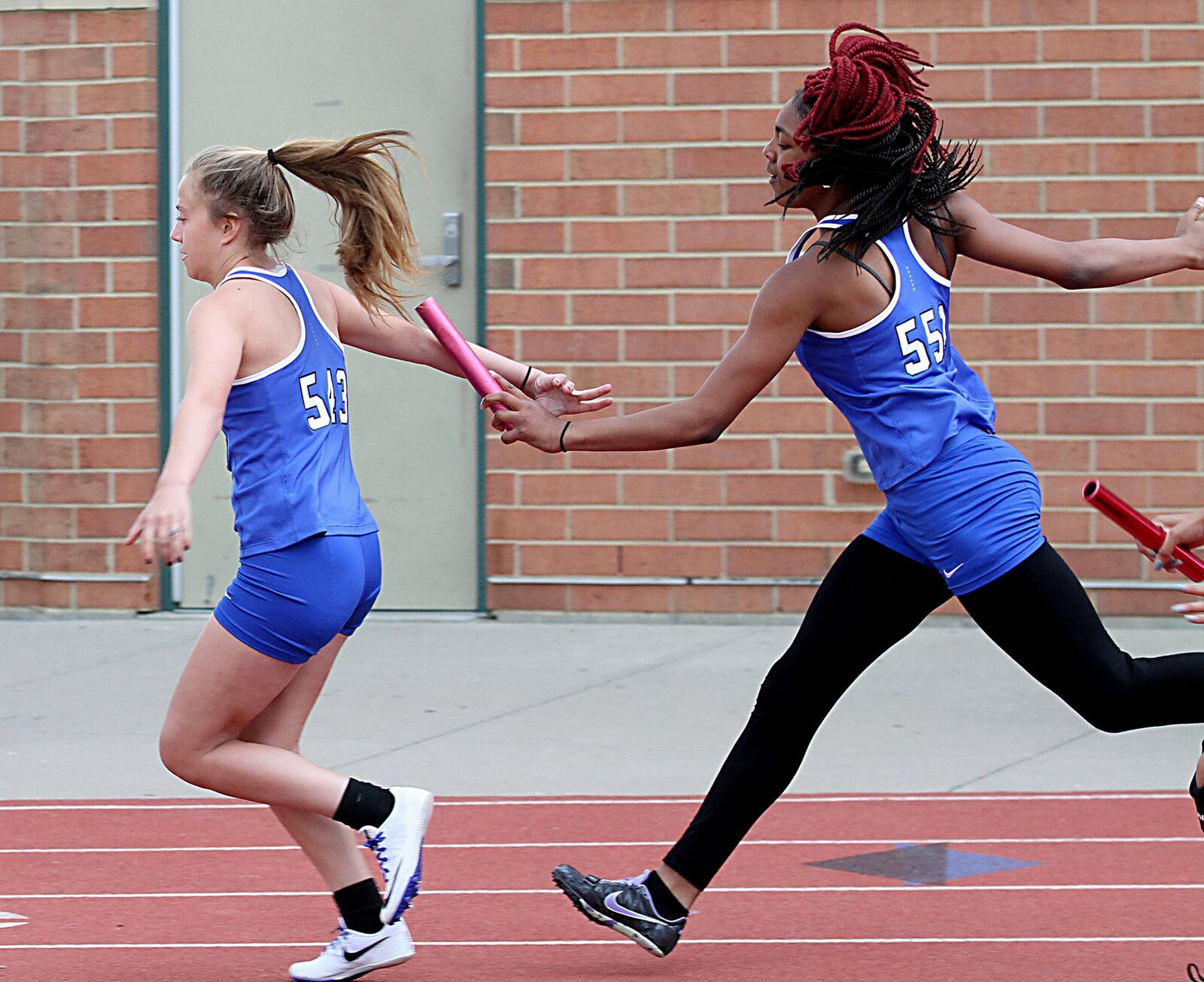 Hamilton’s Lexi Taylor takes the baton from teammate Cici Riggins during the Greater Miami Conference track & field meet on Dwire Field at Atrium Stadium in Mason on Friday. CONTRIBUTED PHOTO BY E.L. HUBBARD