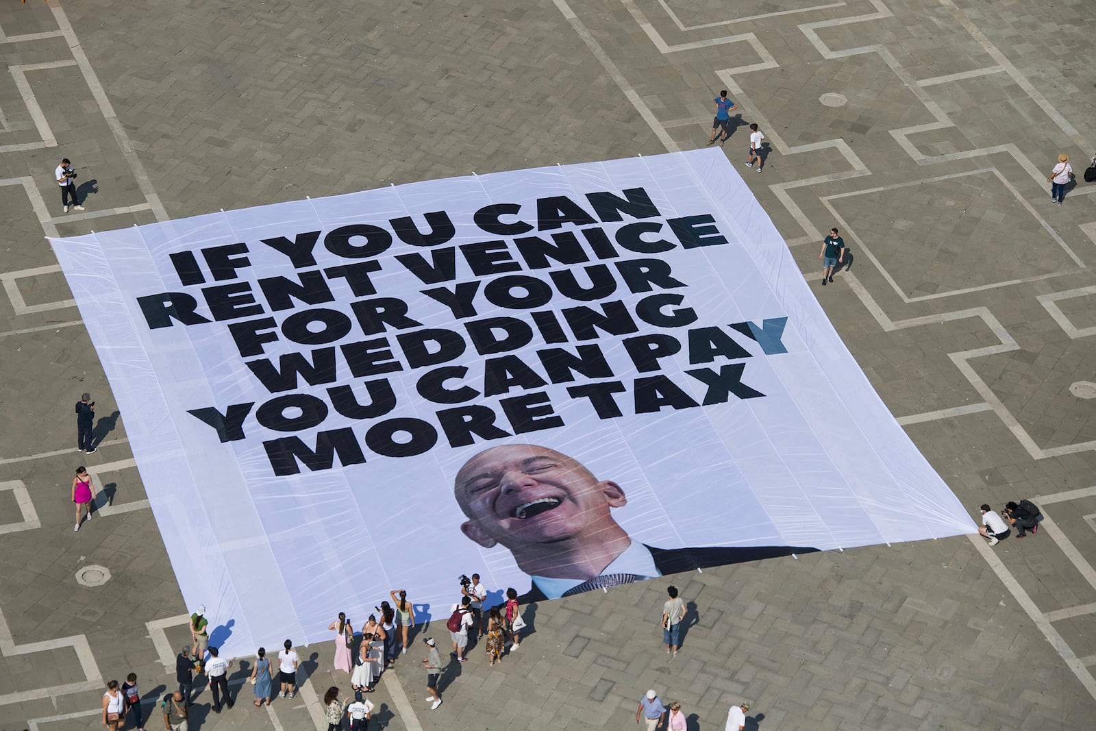 This photo released by Greenpeace shows a large banner against Amazon founder Jeff Bezos' planned wedding, in St. Mark Square, in Venice, Italy Monday, June 23, 2025. (Greenpeace via AP)