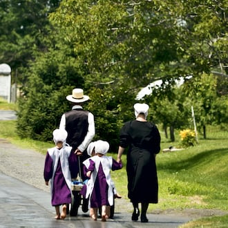 An Amish family walks bare feet over a country road. ISTOCK
