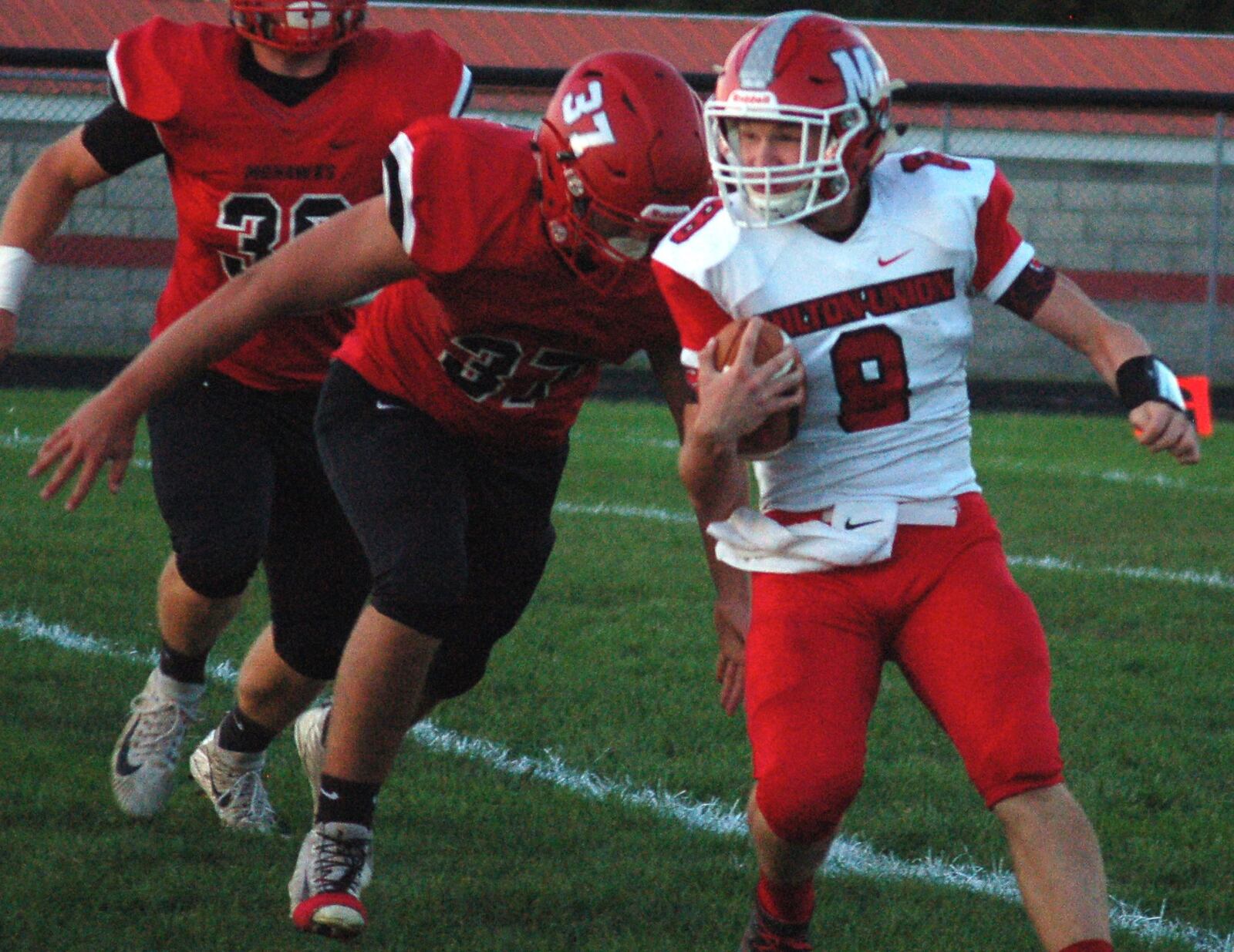 Milton-Union quarterback William Morris tries to avoid Madison’s Tanner Limon last Friday night at Brandenburg Field in Madison Township. The host Mohawks won 46-0. CONTRIBUTED PHOTO BY JOHN CUMMINGS