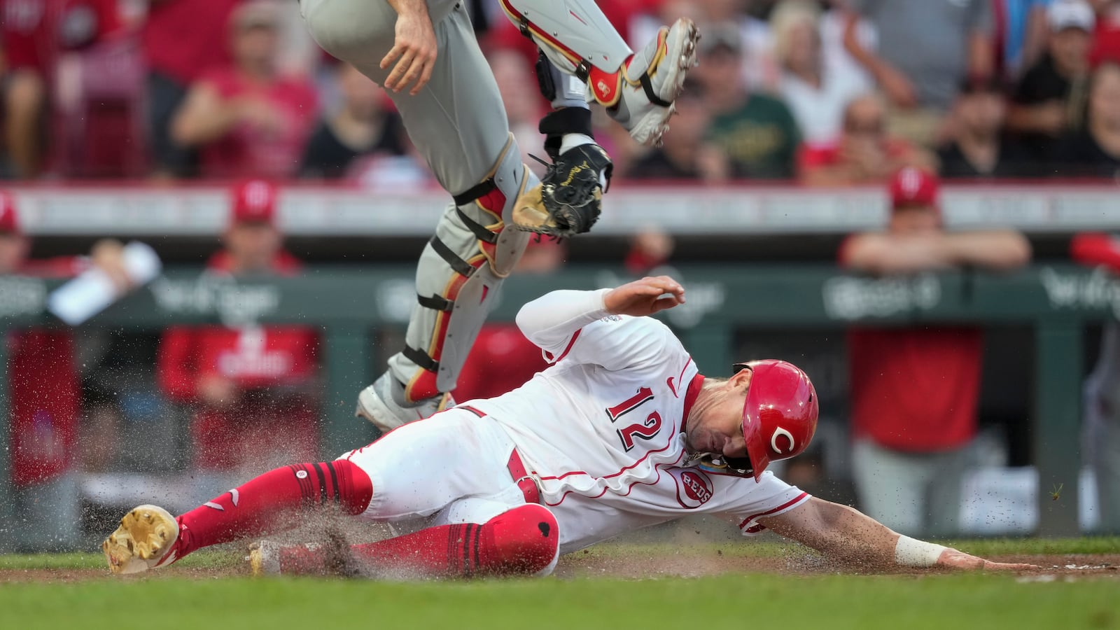 Cincinnati Reds' Austin Hays slides safe at home under leaping Philadelphia Phillies catcher J.T. Realmuto on a single hit by Noelvi Marte during the sixth inning of a baseball game Wednesday, Aug. 13, 2025, in Cincinnati. (AP Photo/Carolyn Kaster)