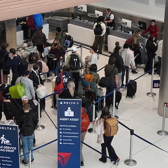 Travellers queue up at a check-in counter for Delta Airlines in Denver International Airport Friday, Dec. 19, 2025, in Denver. (AP Photo/David Zalubowski)