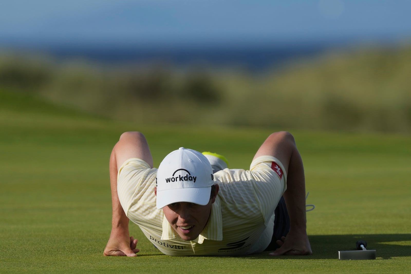 Matt Fitzpatrick of England lies down on the 15th green to look at the lie of his putt during the third round of the British Open golf championship at the Royal Portrush Golf Club, Northern Ireland, Saturday, July 19, 2025. (AP Photo/Jon Super)
