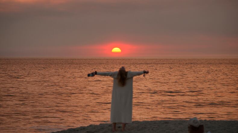 Screen writer and actress Sarah Newcome expresses her gratitude to God during sunset as a plume of smoke from the Franklin Fire rises over the ocean Tuesday, Dec. 10, 2024, in Malibu, Calif. (AP Photo/Damian Dovarganes)