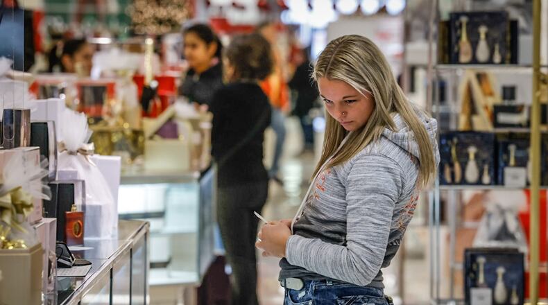 A shopper in Macy's at the Dayton Mall peruses the fragrance section of the store Wednesday December 21, 2022. The Dayton Mall was busy with Christmas just days away and online shipping deadlines passed. JIM NOELKER/STAFF