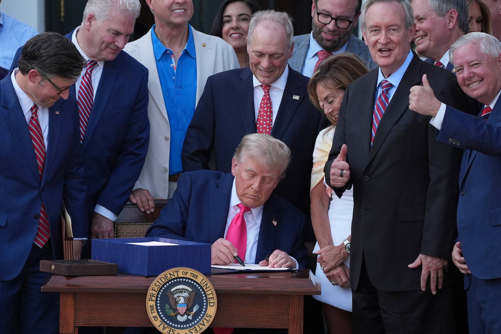 President Donald Trump signs his signature bill of tax breaks and spending cuts at the White House, Friday, July 4, 2025, in Washington, surrounded by members of Congress. (AP Photo/Evan Vucci)