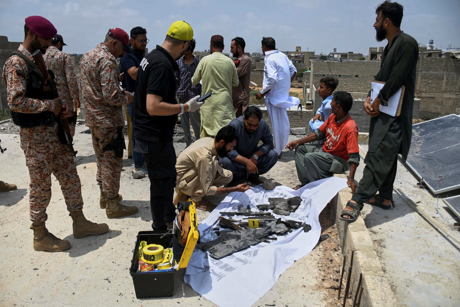 Paramilitary soldiers stand guard as investigators collect pieces of a suspected Indian drone at the site of a drone crash in Karachi, Pakistan, Thursday, May 8, 2025. (AP Photo/Fareed Khan)