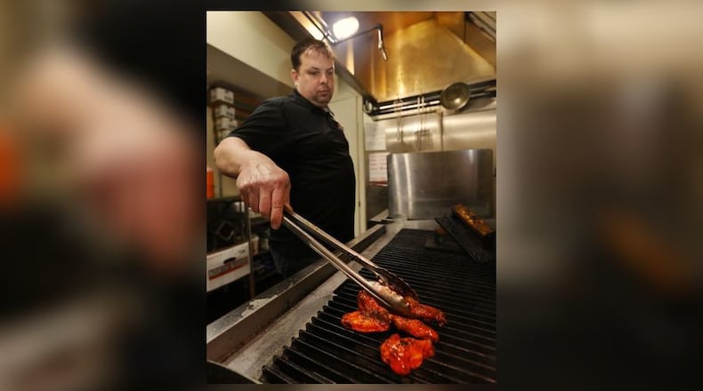 Brent Dalton cooks an order of chicken wings on the grill at Brent's Smokin' Butts on Central Avenue in Middletown. His business normally is closed on Sundays but it's taking pre-orders that can be picked up on Sunday for the Super Bowl. NICK GRAHAM/STAFF