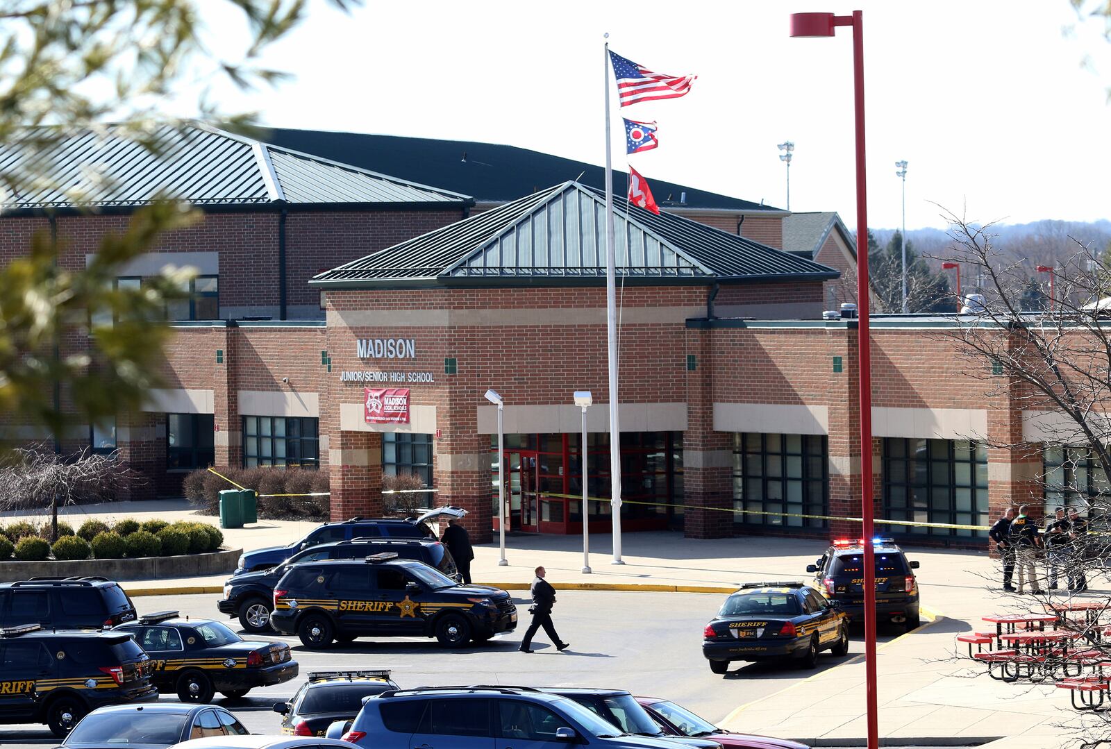 FILE— In this file photo from Feb. 29, 2016, Butler County Sheriff Deputies stand on the scene at Madison Local Schools, in Madison Township in Butler County, Ohio, after a school shooting. After the 2016 shooting, a group of parents sued the district in September 2018 to prevent teachers from being armed without extensive training. The Ohio Supreme Court ruled Wednesday, June 23, 2021 that armed school employees must undergo an approved basic peace-officer-training program or have 20 years experience as a police officer. (Cara Owsley/The Cincinnati Enquirer via AP)