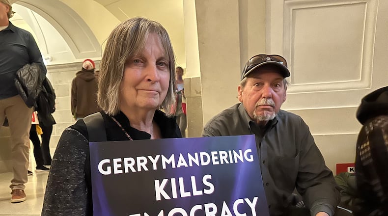 Paula Wood holds a sign protesting Missouri’s congressional redistricting effort while sitting beside her husband, Tim Wood, during a rally on Jan. 21, 2026, at the state Capitol in Jefferson City, Mo. (AP Photo/David A. Lieb)