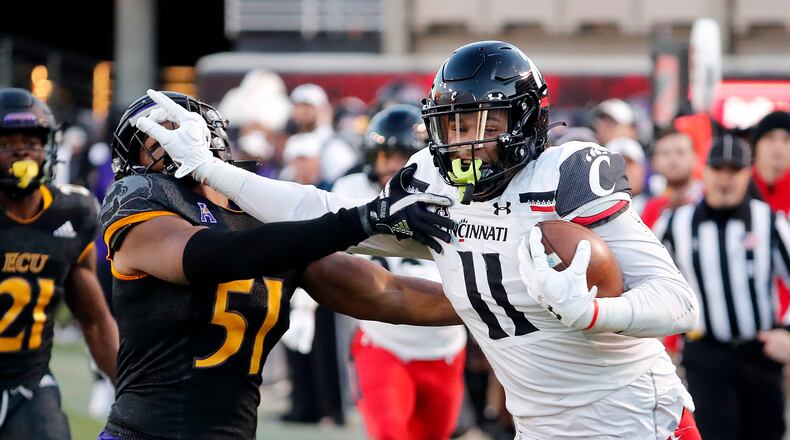 Cincinnati's Leonard Taylor, a Springfield High graduate, stiff-arms East Carolina's Aaron Ramseur (51) after catching the ball during the first half of an NCAA college football game in Raleigh, N.C., Friday, Nov. 26, 2021. (AP Photo/Karl B DeBlaker)