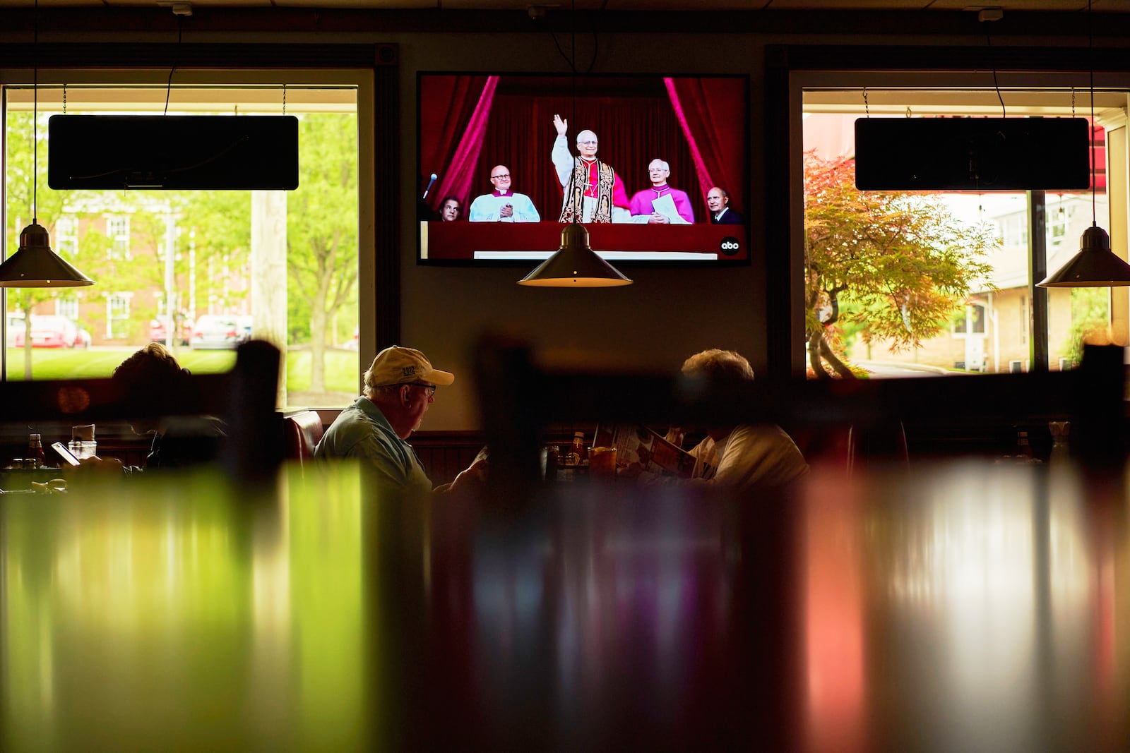 Patrons watch live coverage of the newly elected Pope Leo XIV from St. Peter's Basilica at the Vatican while having lunch at Ron's Roost Chicken Restaurant, Thursday, May 8, 2025, in Cincinnati. (AP Photo/Carolyn Kaster)