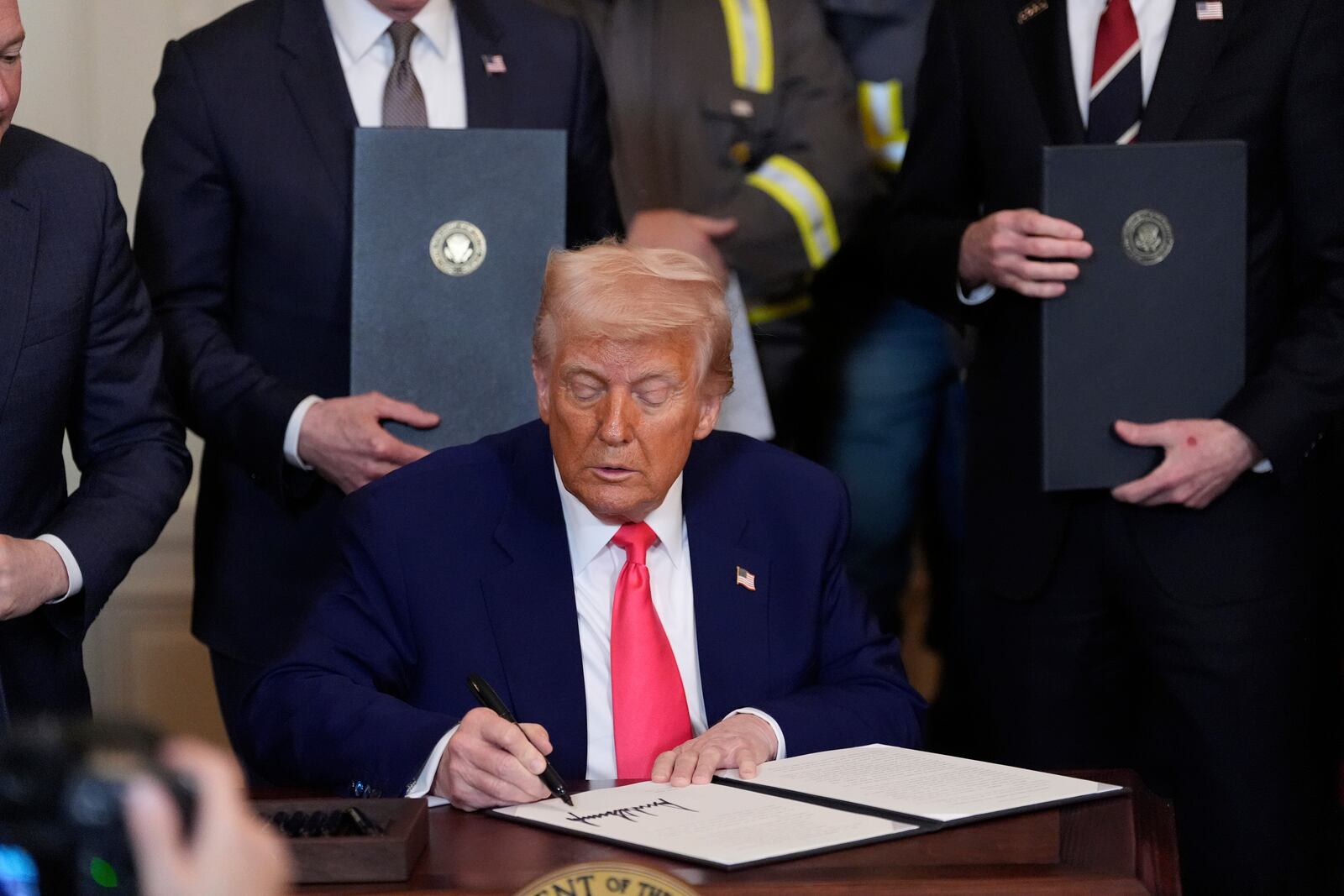President Donald Trump signs an executive order during an event in the East Room of the White House, Tuesday, April 8, 2025, in Washington. (AP Photo/Alex Brandon)