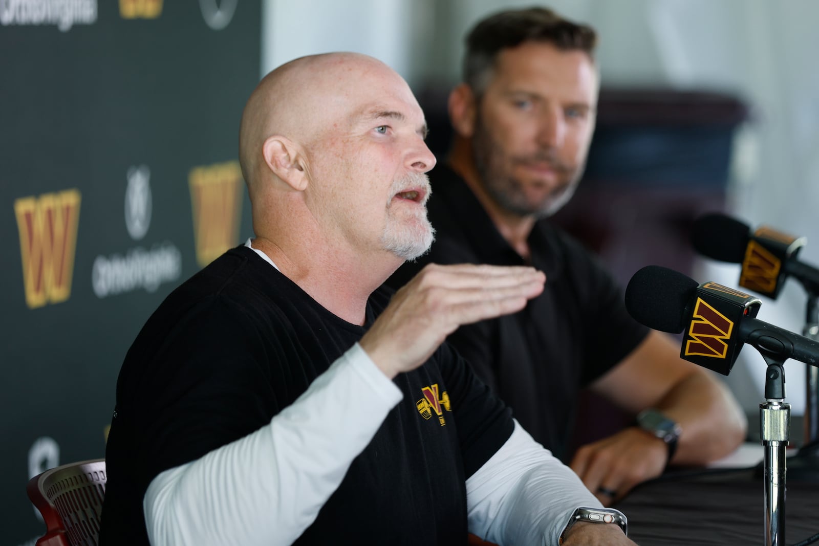 Washington Commanders head coach Dan Quinn, left, speaks as general manager Adam Peters, right, looks on during a news conference at the NFL football team's training camp in Ashburn, Va., Tuesday, July 22, 2025. (AP Photo/Luis M. Alvarez)