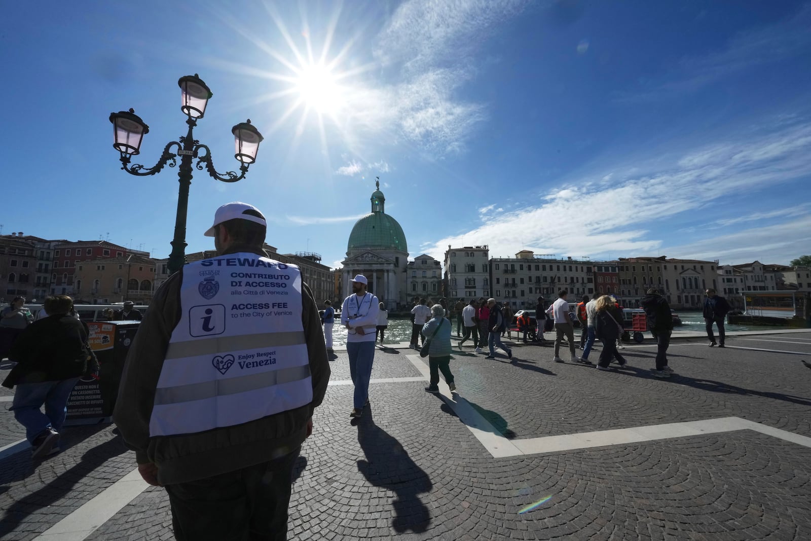 Stewards check tourists' QR codes outside the main train station in Venice, Italy, Friday, April 18, 2025, as the city for a second year is charging day-trippers an arrivals tax. (AP Photo/Antonio Calanni)