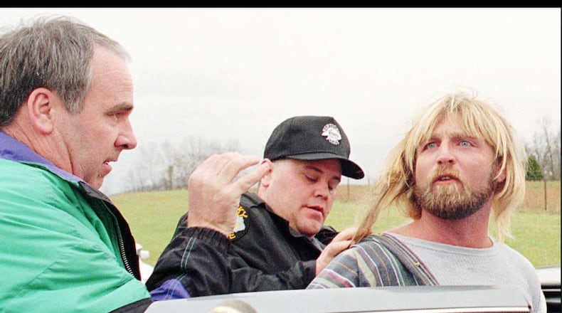 Bob Stephens, left, Kentucky state police detective, and another official put Glenn Rogers in a police cruiser after Rogers was arrested Monday afternoon, Nov. 13, 1995, near rural Waco, Ky. Rogers, 33, is suspected of strangling or stabbing at least four women in California, Louisiana, Mississippi and Florida in the past two months. (AP Photo/The Richmond Register, Phil Poynter)