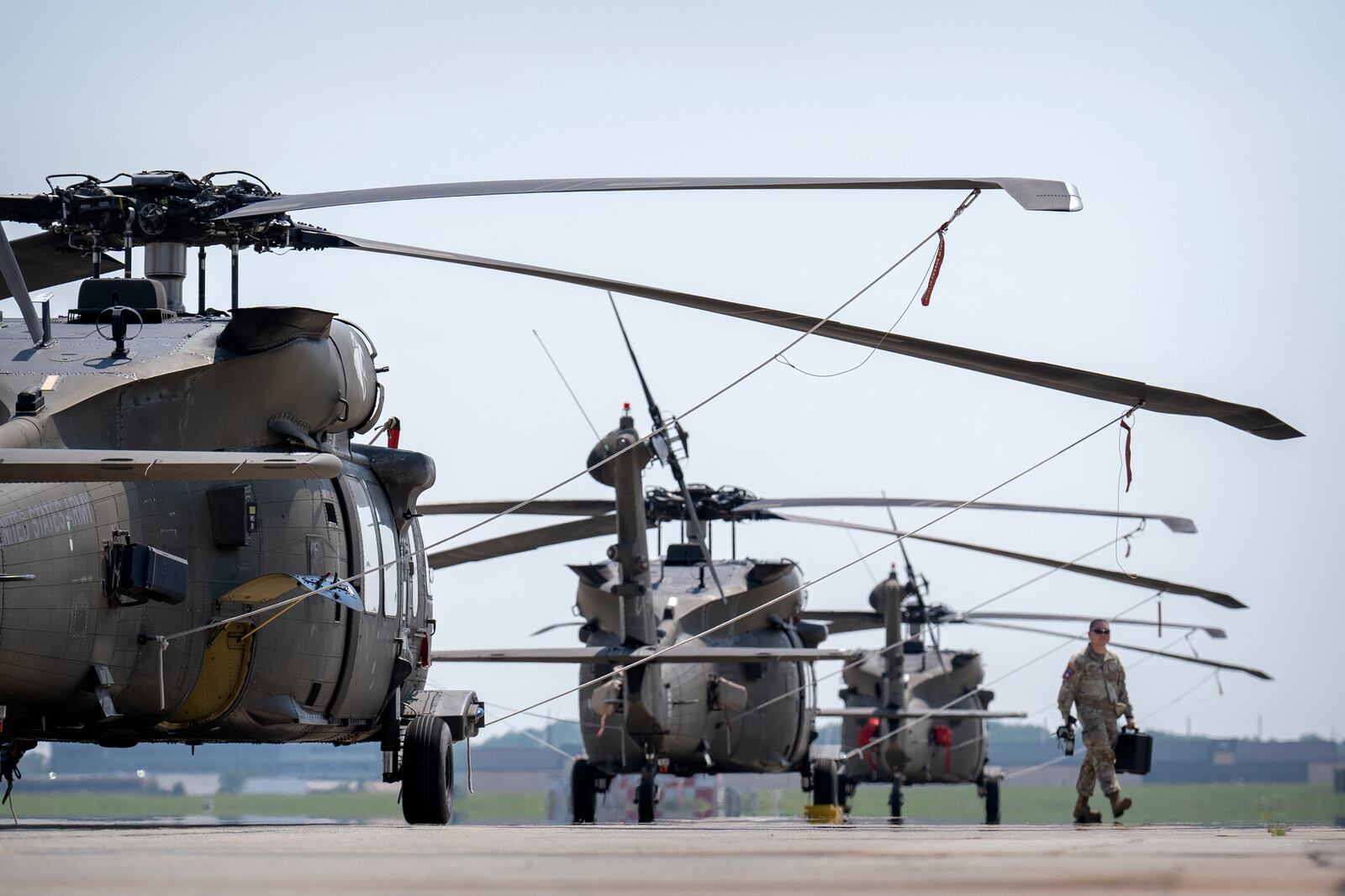 A crew member walks past U.S. Army UH-60M Black Hawk helicopters that will participate in an upcoming military parade commemorating the Army's 250th anniversary and coinciding with President Donald Trump's 79th birthday, at Joint Base Andrews, Md., Thursday, June 12, 2025. (AP Photo/Mark Schiefelbein)