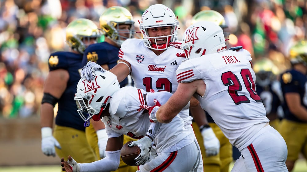 Miami (Ohio) linebackers Corban Hondru, center, and Adam Trick, right, celebrate with defensive back Luke Evans, left, after Evans recovered a fumble during the second half of an NCAA college football game against Notre Dame, Saturday, Sept. 21, 2024, in South Bend, Ind. (AP Photo/Michael Caterina)