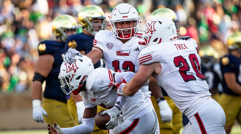 Miami (Ohio) linebackers Corban Hondru, center, and Adam Trick, right, celebrate with defensive back Luke Evans, left, after Evans recovered a fumble during the second half of an NCAA college football game against Notre Dame, Saturday, Sept. 21, 2024, in South Bend, Ind. (AP Photo/Michael Caterina)