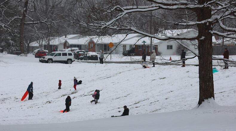Families sled down a hill at Smith Park in New Carlisle Sunday. BILL LACKEY/STAFF