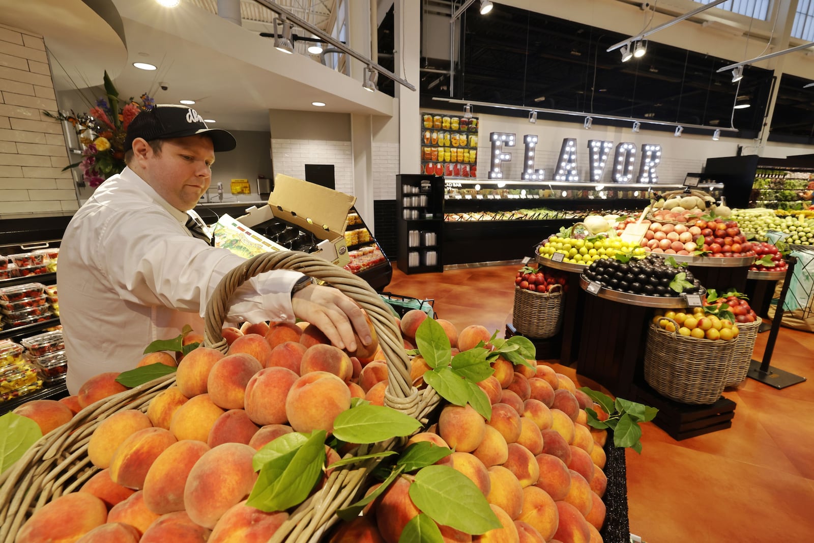 Kenny Rolph stocks peaches during the grand opening at the new Dorothy Lane Market store Wednesday, Aug. 20, 2025 on Mason Montgomery Road in Mason. NICK GRAHAM/STAFF