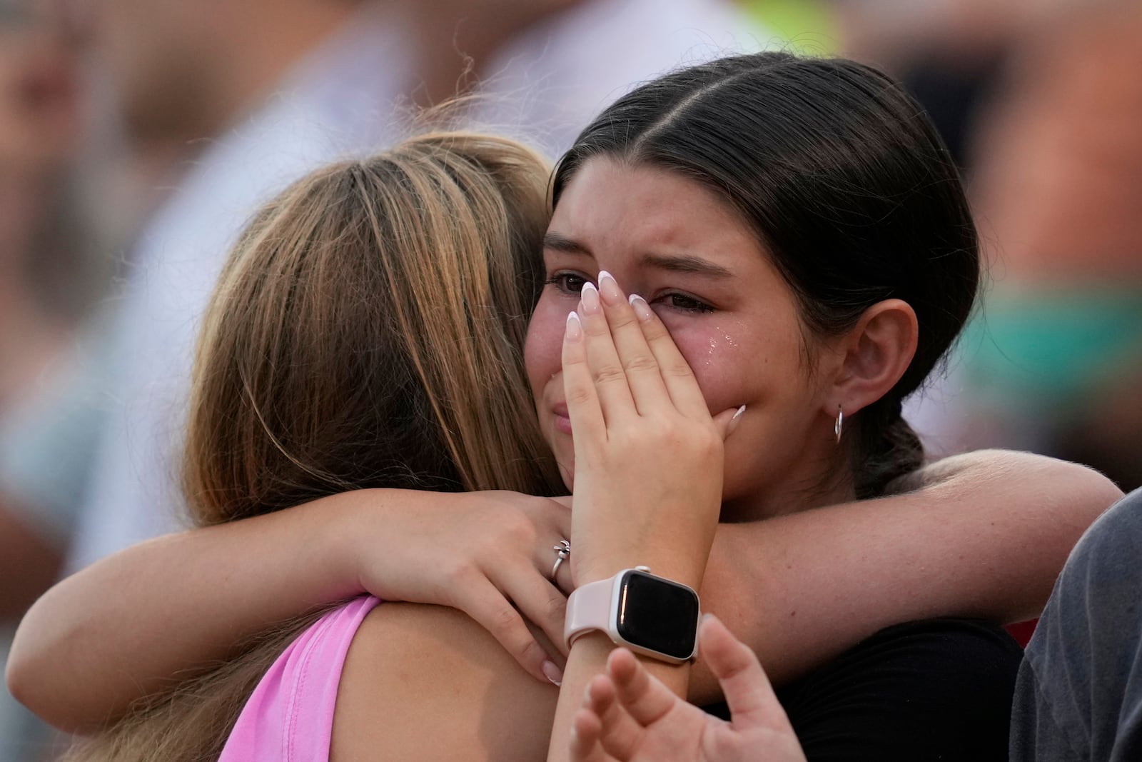 Girls hug during a vigil for flooding victims at Tivy Antler Stadium on Wednesday, July 9, 2025, in Kerrville, Texas. (AP Photo/Ashley Landis)