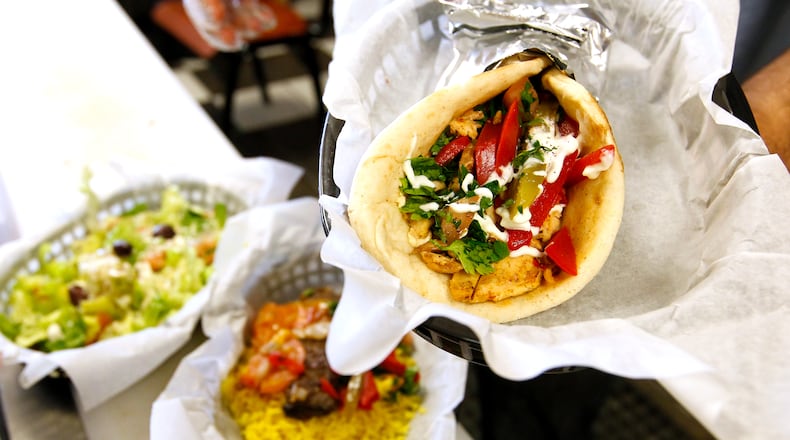 Zane Hamid, owner of Tikka Grill, holds an order of Chicken Shawerma at his recently opened restaurant in West Chester Twp. NICK DAGGY / STAFF