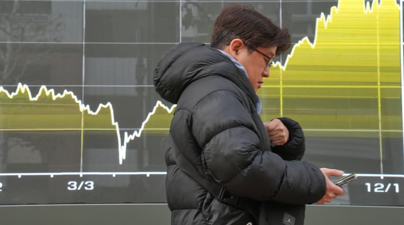 A person walks in front of a chart showing Japan's Nikkei index at a securities firm Friday, Dec. 19, 2025, in Tokyo. (AP Photo/Eugene Hoshiko)