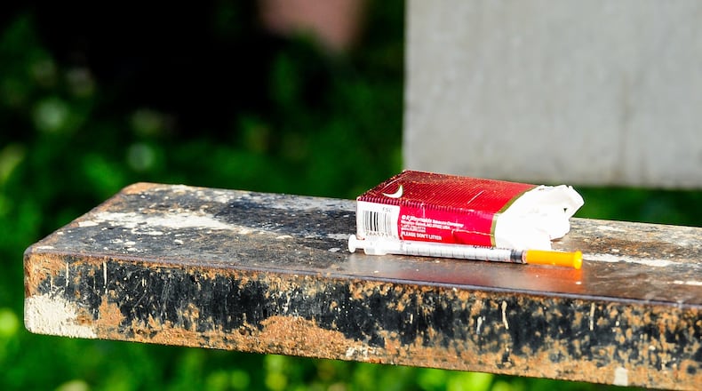 Opioids and heroin have been a growing problem in Butler County and Ohio for the past several years. More and more people become addicted and die from the drug that is now commonly laced or cut with other stronger opioids, like fentanyl and carfentanil. Pictured is a man in the summer of 2017 in the background laying behind a convenience store in Middletown after a drug overdose. NICK GRAHAM/STAFF