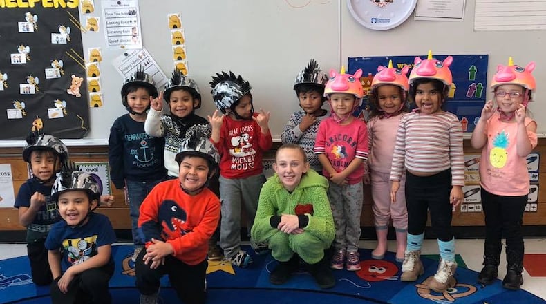 Ross Township 12-year-old Taya Estes, center front row in Grinch costume, didn't let the coronavirus stop her family tradition of giving Christmas gifts to area pre-school students. Taya spent past years baking and selling cookies to buy gifts - she is seen here in 2019 after giving bike helmets - but this year had to change due to coronavirus. (Provided Photo\Journal-News)