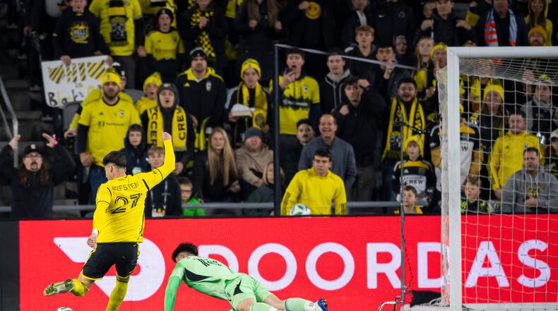 Columbus Crew forward Max Arfsten (27) kicks the ball as FC Cincinnati goalkeeper Roman Celentano (18) tries to defend during the first half of Game 2 in the first round of MLS soccer's Eastern Conference playoffs, Sunday, Nov. 2, 2025, in Columbus. (AP Photo/Tanner Pearson)