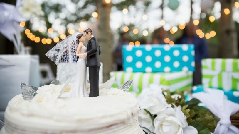 Bride and groom cake topper on cake (stock photo).