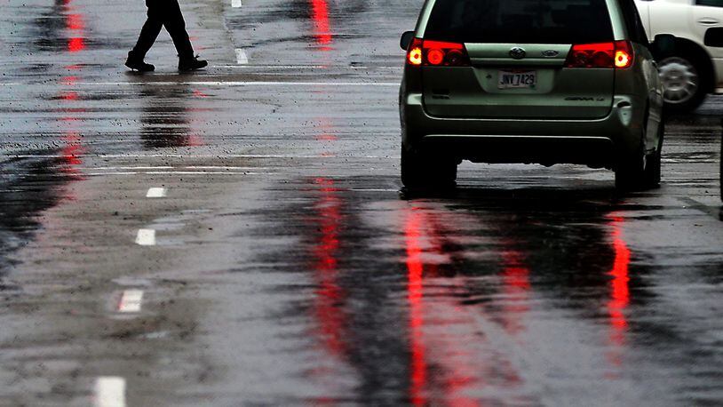 A man with a red umbrella matches the red traffic lights reflected on the wet roadway Feb. 22. Heavy rain drenched the area forcing some roads to be closed. BILL LACKEY/STAFF