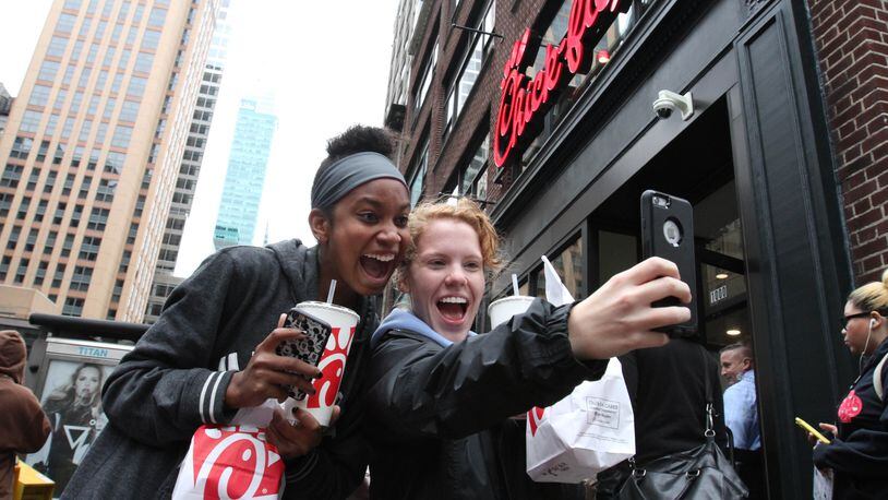 Jaimie Cranford, right, takes a photograph with Mariah Reives outside the Chick-fil-A store in New York on the store's opening day Saturday Oct. 3, 2015. Cranford, originally from South Carolina, and Reives, originally from North Carolina, currently live in New York. (AP Photo/Tina Fineberg)