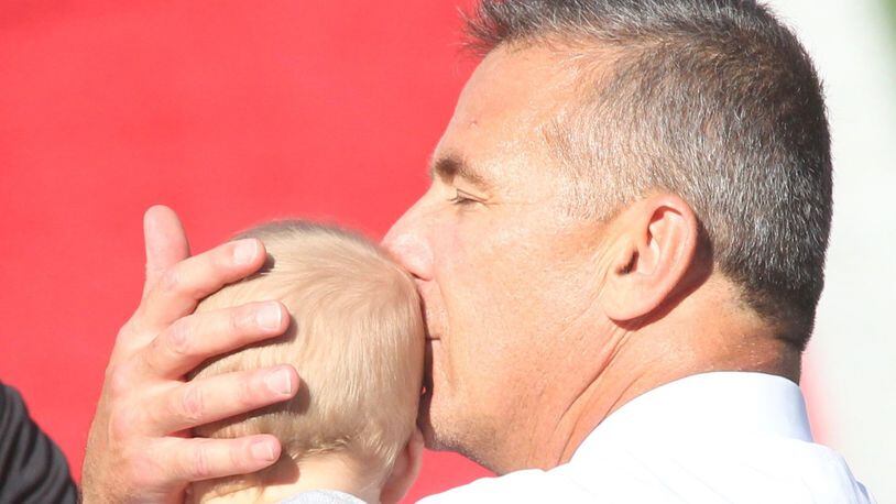 Ohio State’s Urban Meyer kisses his grandson Troy at Ohio Stadium before a game against UNLV on Saturday, Sept. 23, 2017, in Columbus. David Jablonski/Staff