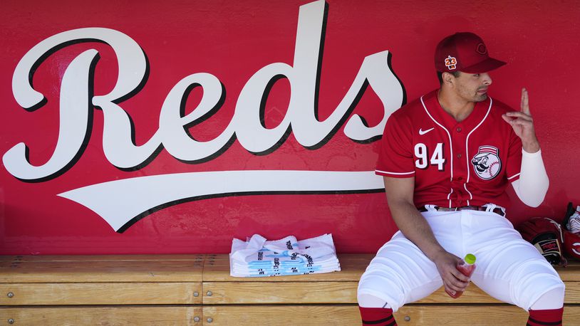 Cincinnati Reds' Christian Encarnacion-Strand talks to a teammate in the dugout prior to a spring training baseball game against the Cleveland Guardians, Saturday, Feb. 25, 2023. (AP Photo/Ross D. Franklin)