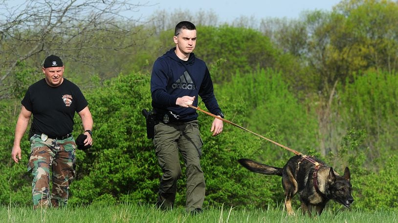 Franklin police Officer Olen Keil follows K-9 Liza following a ground scent during a tracking exercise in Kettering on Thursday. Kettering police Lt. Brad Lampert, left, evaluates how the K-9 team is doing as it tracks down the dog's toy. Kettering police is training several K-9s in the area for free so that there is a standardized level of training for the dogs and handlers. The 12-week course ends June 30 with an evaluation by the Ohio Peace Officers Training Academy. If they pass the evaluation, the dog will receive state K-9 certification. MARSHALL GORBY\STAFF