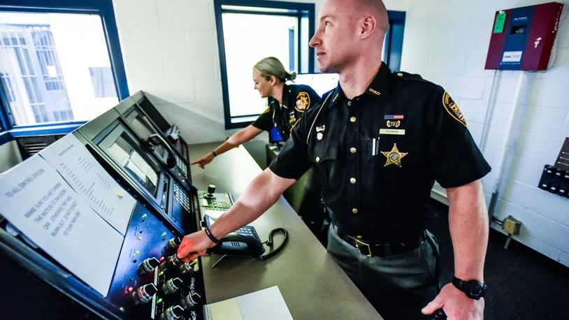 Butler County Sheriff’s Office corrections officers Waylon Thomas and Hannah McCarthy stand in the control room of the old Butler County Court Street Jail that was re-opened recently, in part because a new law takes effect July 1 that prohibits judges from sending felony five offenders to prison. Sheriff’s Chief Deputy Tony Dwyer said they also have more contract prisoners than local ones, a situation that requires a careful balancing act between pulling in more revenue for boarding inmates and having to hire more people full-time. One floor of the jail is in operation and another floor is ready for new inmates. NICK GRAHAM/STAFF