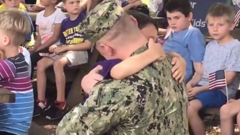 John Meredith hugs his son Aden after surprising him at school Monday.