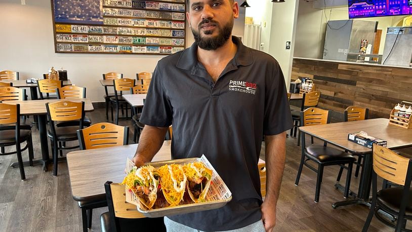 Nawaf Nayyef from Prime BBQ Smokehouse in Monroe delivers a plate of tacos to a customer. The restaurant has added to its menu, including three tacos on Taco Tuesdays for $8.99. RICK McCRABB/STAFF
