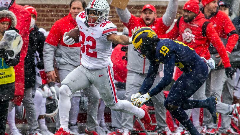 Ohio State running back TreVeyon Henderson (32) tries to fend off Michigan defensive back Rod Moore (19) in the first quarter of an NCAA college football game in Ann Arbor, Mich., Saturday, Nov. 27, 2021. (AP Photo/Tony Ding)