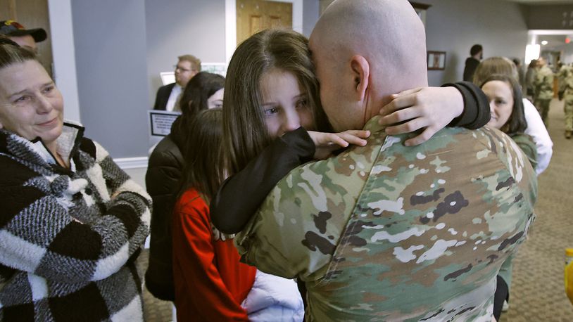 With tears in her eyes, Zoey Wildermuth hugs her father, Sgt. Darrick Cunningham, during a Call to Duty Ceremony Friday, Jan. 12, at the First Christian Church. Cunningham is being deployed with 30 other members of the Ohio National Guard's 1137th Signal Comapany, located in Springfield. BILL LACKEY/STAFF 