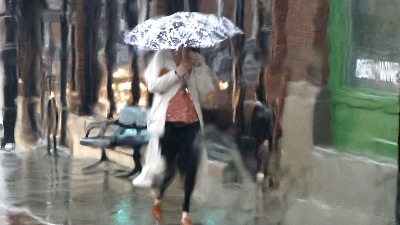 A woman with an umbrella is seen through a rain soaked window as she walks along South Fountain Avenue during a thunderstorm Tuesday, March 5, 2024. The sunshine and blue skies Tuesday morning quickly turned dark in the afternoon with a thunderstorm. BILL LACKEY/STAFF