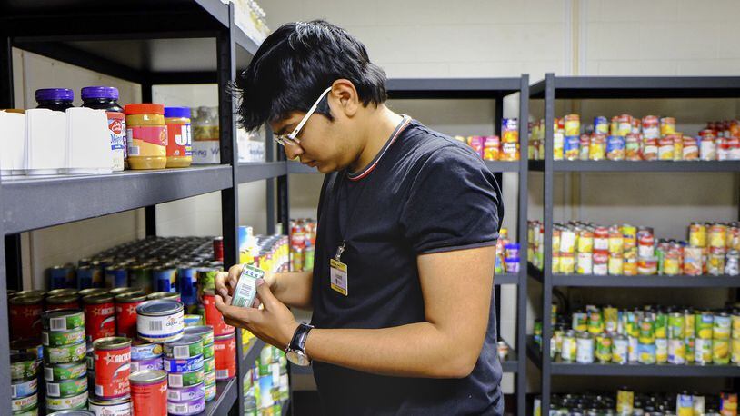 In this Feb. 5, 2016, photo, Vedant Kale, a first-year finance student from Aurangabad, India, shelves donated food in a new pantry at the University of Toledo. Photo by Jetta Fraser/The Blade